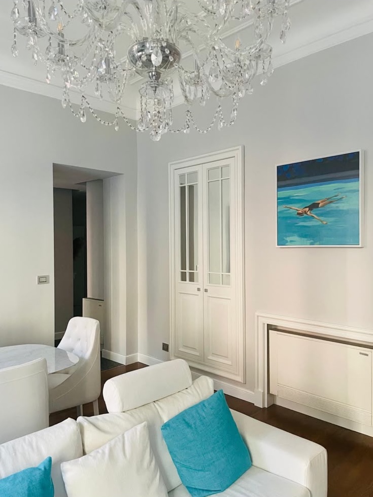 The living room from the window: crystal chandelier and the painting of a swimmer