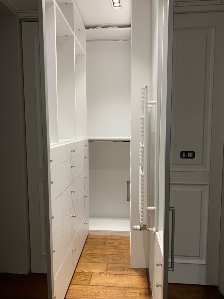 The walk-in closet, lined with white wardrobes