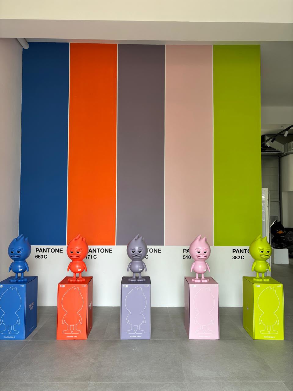 The colour wall: five stripes, five figures, each on a plinth in its own shade